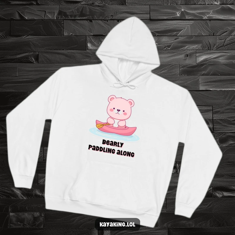 Funny pink bear hoodie featuring a bear serenely kayaking, perfect for cozy relaxation and peaceful, humorous vibes.